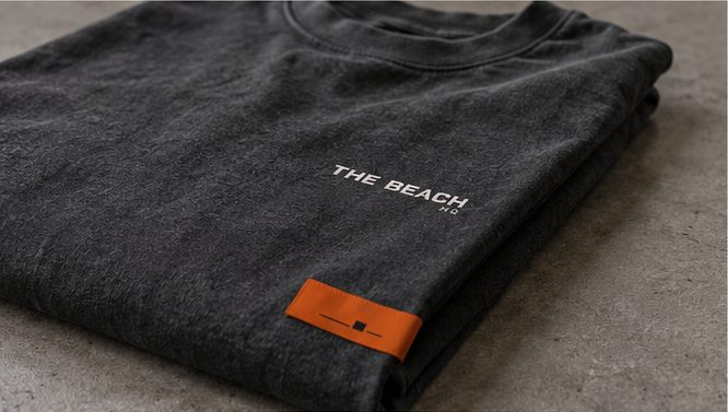 Concept: folded graphite shirt with a small wordmark print and an orange woven label